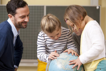 Lehrer und Schüler betrachten den Globus im Klassenzimmer - MFRF000133