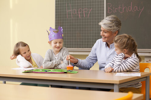 Lehrerin und Schülerinnen feiern Geburtstag im Klassenzimmer - MFRF000140