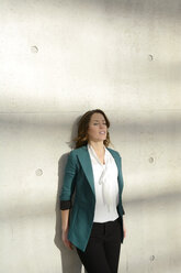 Businesswoman leaning against concrete wall - BFRF001002