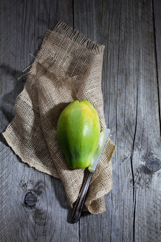 Papaya on burlap and knife on wood stock photo