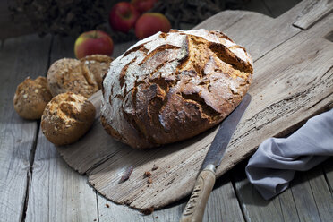 Krustiges Brot und altes Brotmesser auf Schneidebrett, Körnerbrötchen - CSF024732