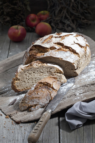 Krustiges Brot und altes Brotmesser auf Schneidebrett, lizenzfreies Stockfoto
