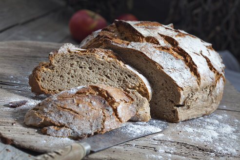 Krustiges Brot und altes Brotmesser auf Schneidebrett - CSF024735