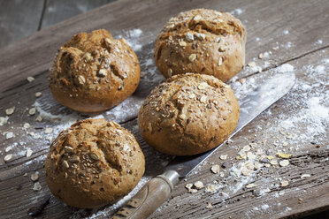 Vollkornbrötchen, Mehl und altes Brotmesser auf Holz - CSF024737