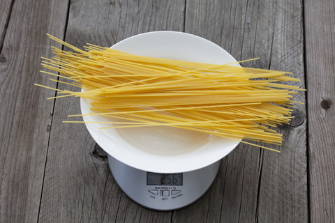 Reihe Spaghetti auf Teller und Waage auf Holz, lizenzfreies Stockfoto
