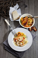 Spaghetti mit Scampis und Gemüse auf Teller, Schale mit Tomatenspiralen und Zucchini, getrocknete Tomate - CSF024743