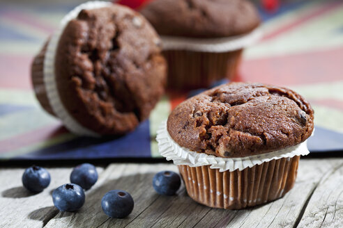 Schokoladenmuffins und Blaubeeren auf Holz, englische Flagge - CSF024759