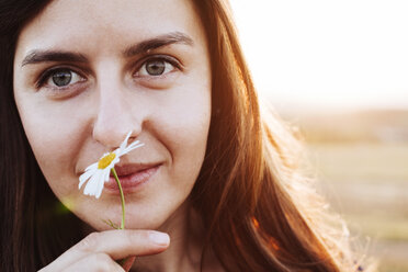 Porträt einer lächelnden Frau, die an einer Blume riecht - BZF000069
