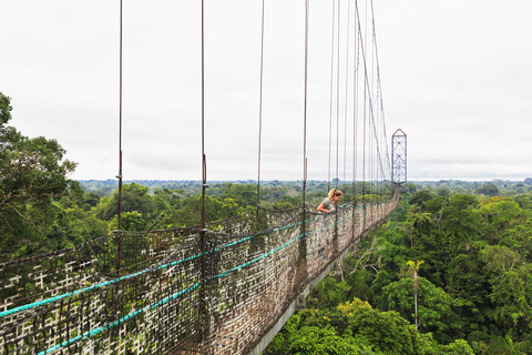 Ecuador, Amazonasgebiet, Tourist auf Hängebrücke über Regenwald, lizenzfreies Stockfoto