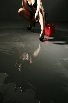 Young woman wearing lingerie mirroring in spilled fuel - VEF000038