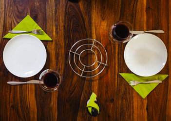 Gedeckter Holztisch mit Tellern und Rotwein - KRPF001341