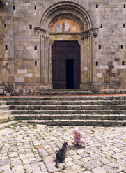 Italien, Toskana, Montefollonico, Mädchen und Katze vor einer Kirche - GSF001005