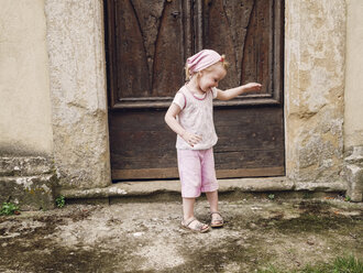 Italy, Tuscany, Montefollonico, girl at wooden door - GSF000983