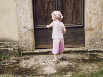 Italy, Tuscany, Montefollonico, girl at wooden door - GSF000988