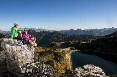 Austria, Altenmarkt-Zauchensee, young couple with mountain bikes in the mountains - HHF005196