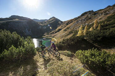 Österreich, Altenmarkt-Zauchensee, junges Paar mit Mountainbikes in den Bergen - HHF005199