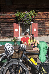 Österreich, Altenmarkt-Zauchensee, junges Paar mit Mountainbikes auf Almhütte - HHF005202
