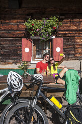 Österreich, Altenmarkt-Zauchensee, junges Paar mit Mountainbikes auf der Almhütte beim Selfie machen - HHF005211