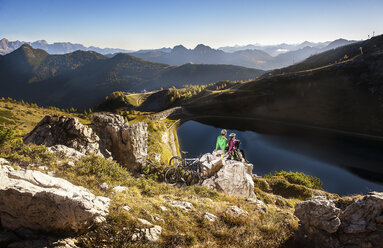 Austria, Altenmarkt-Zauchensee, young couple with mountain bikes in the mountains - HHF005204