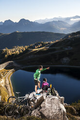 Austria, Altenmarkt-Zauchensee, young couple with mountain bikes in the mountains - HHF005212