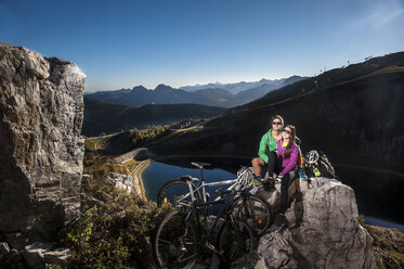 Austria, Altenmarkt-Zauchensee, young couple with mountain bikes in the mountains - HHF005209