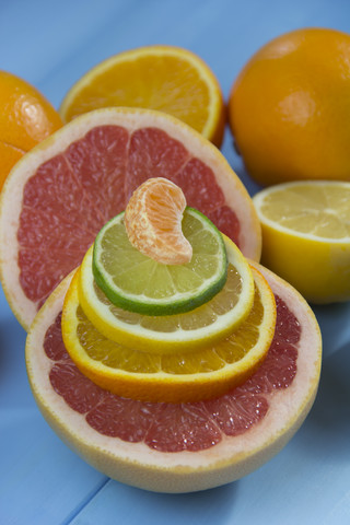 Stapel von Orangen-, Limetten-, Zitronen- und Mandarinenscheiben auf einer halben Grapefruit, lizenzfreies Stockfoto