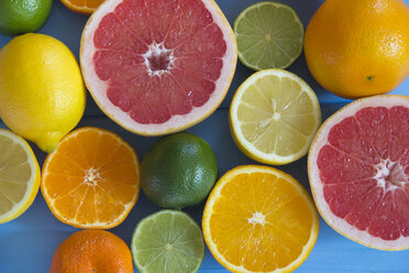 Whole and halves of orange, grapefruit, lime, lemon and tangerine on blue ground - YFF000334