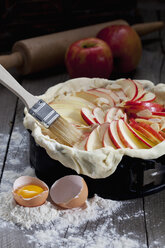 Raw apple pie in cake pan and ingredients on wood - CSF024779