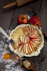 Roher Apfelkuchen in Kuchenform und Zutaten auf Holz - CSF024778