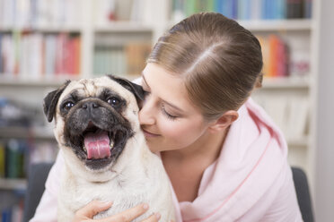 Young woman cuddling with pug - DRF001597