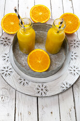 Orangen-Smoothie in Glasflaschen mit Strohhalm auf Teller - SARF001452