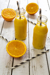 Orange smoothie in glass bottles, straws on wood - SARF001453