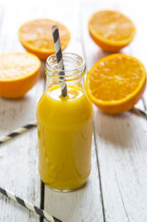Orangen-Smoothie in Glasflasche, Strohhalm auf Holz - SARF001454