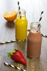 Orange and strawberry smoothie in glass bottles, straws and fruits - SARF001458