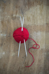 Red ball of wool and knitting needles on wood - CRF002634