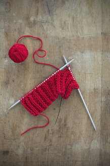 Red ball of wool and knitting on wood - CRF002639