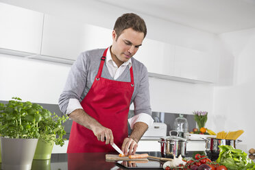 Man cutting carrots in kitchen - PDF000828