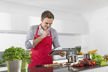 Lächelnder Mann, der beim Kochen ein digitales Tablet benutzt - PDF000830