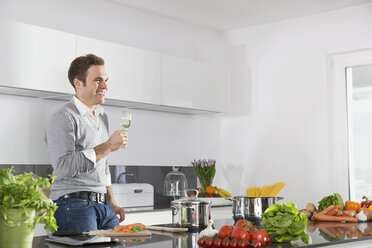 Man relaxing with glass of sparkling wine in kitchen - PDF000837