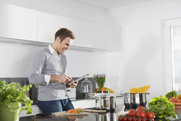 Smiling man using digital tablet in the kitchen - PDF000838