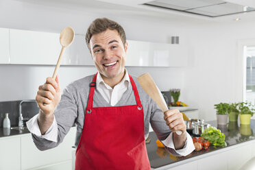 Porträt eines lächelnden Mannes mit roter Schürze und Küchenutensilien - PDF000843