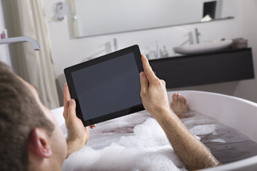 Mann mit digitalem Tablet in der Badewanne sitzend - PDF000878