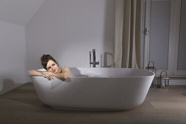 Smiling woman relaxing in modern bathtub - PDF000887