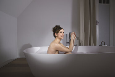 Smiling woman relaxing in modern bathtub - PDF000890