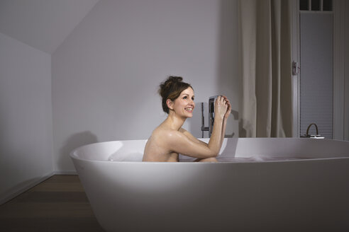 Lächelnde Frau entspannt sich in einer modernen Badewanne - PDF000890