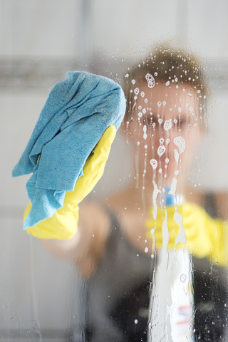 Frau reinigt Glasscheibe, lizenzfreies Stockfoto