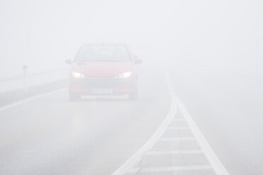 Austria, red car driving through heavy fog - EJWF000710