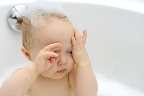 Baby-Mädchen in einer Badewanne wischt Badeschaum - LHF000443