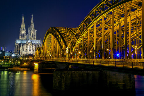 Germany, Cologne, illuminated Cologne Cathedral and Hohenzollern bridge at night - YRF000075