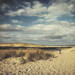 France, Contis-Plage, man walking along the dunes - DWIF000453